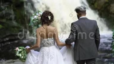 年轻的新婚夫妇在瀑布附近举行婚礼